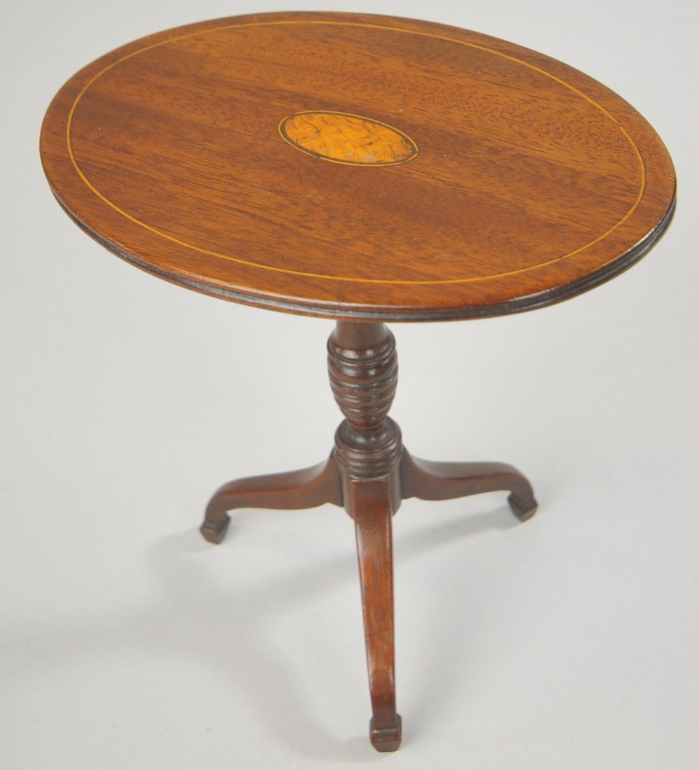 MINIATURE SALESMAN SAMPLE TEA TABLE: circa 1920, three-legged mahogany tilt top tea table with satinwood inlay on a turned column base. Ex. Beverly Darling Collection. Table top 4 3/4" x 3 /38", 5" h.