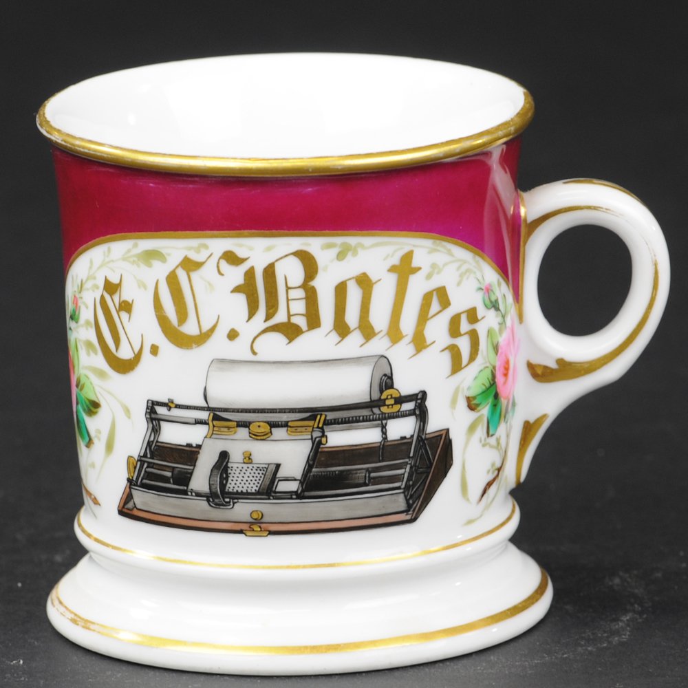 HALLS TYPEWRITER SHAVING MUG: D & C mark with G.W.G. artist initials on base, large center image of an early Hall's typewriter flanked by floral décor on both sides and highlighted by deep purple color band, gold gilt name reads,
