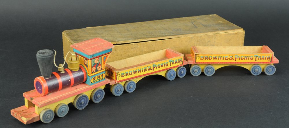 BOXED BLISS BROWNIE'S PICNIC TRAIN: Paper litho over wood, includes locomotive and two open gondolas, each with colorful sides, loco has Brownie figures at windows, contained in wooden box, broken piece to lid, break to bottom groove po