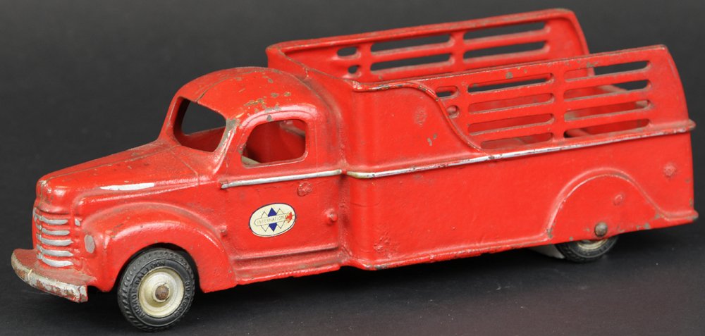 1941 INTERNATIONAL STAKE TRUCK: Arcade, cast iron, painted in red overall, painted IH decals on doors, open stake body, enclosed cab, black rubber tires. 11 1/2" l.