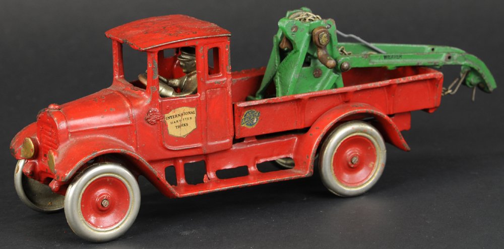 ARCADE "RED BABY" WRECKER: c. late 1920's, cast iron, painted in red, IH truck contains a green "Weaver" boom with nickel hoist and lever, wire chain and hook, seated nickel driver, disc wheels, decals on doors. 12" l.
