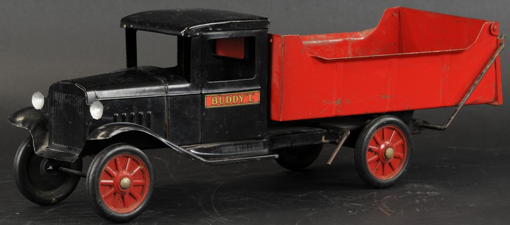 BUDDY 'L' MANUAL DUMP TRUCK: Pressed steel, black enclosed cab, open red body, manual lever on side, embossed rubber wheels have spoke pattern, decals on door, dummy lights. 21" l.