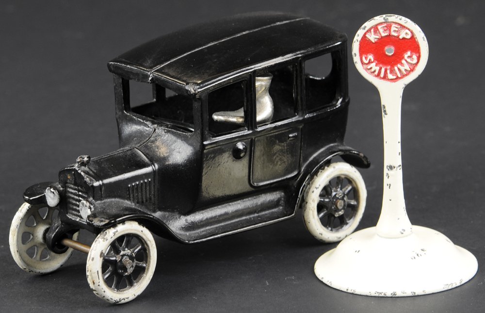ARCADE MODEL 'T' CENTER DOOR SEDAN: Cast iron, painted in black w/gold highlighting, black painted spoke wheels, together with "Keep Smiling" road sign. 6 1/2" l.