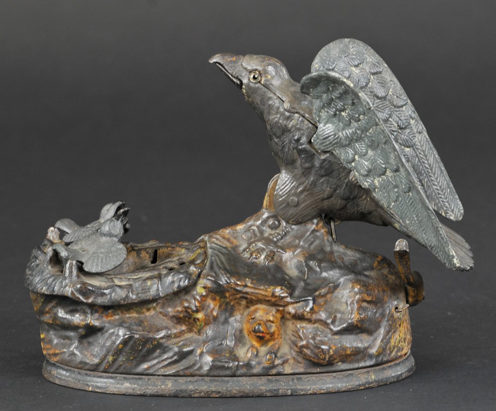 EAGLE & EAGLETTS MECHANICAL BANK: J & E Stevens Co., designed by Charles M. Henn, Chicago, IL, patented 1/23/1883. Place a coin in the eagle’s beak, press the lever and the eaglets rise from the nest, actually crying for food. As th