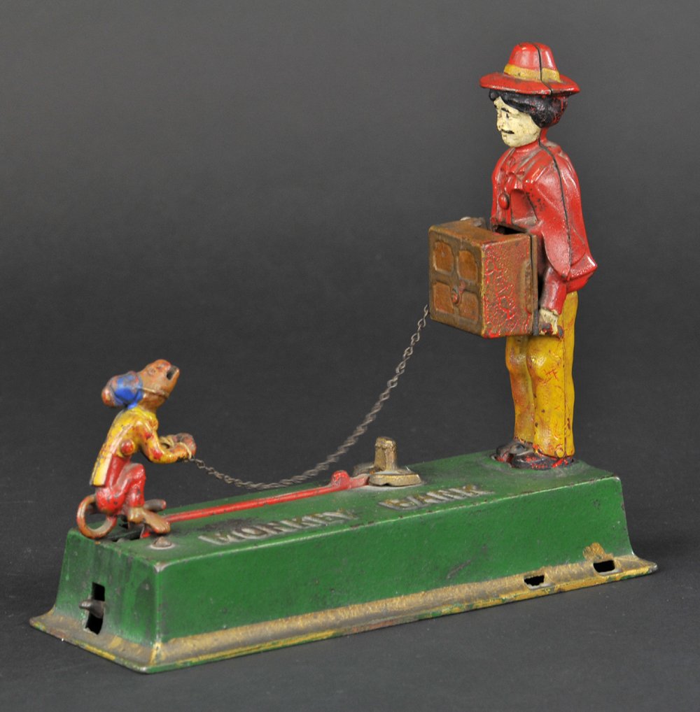 MONKEY MECHANICAL BANK: Hubley Mfg. Co. Place a coin in the monkey’s mouth and press the lever, he jumps and deposits the coin into the organ. To reset, move the monkey to his original position.