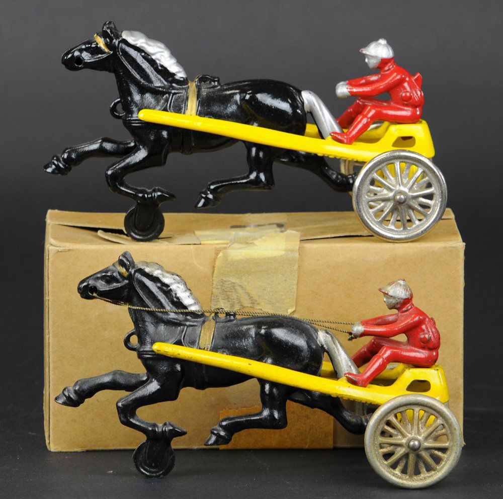 LOT OF TWO KENTON SULKY TOYS: One boxed, both cast iron, black horses, yellow sulkies, nickel spoke wheels, red drivers. 6 3/4" l.