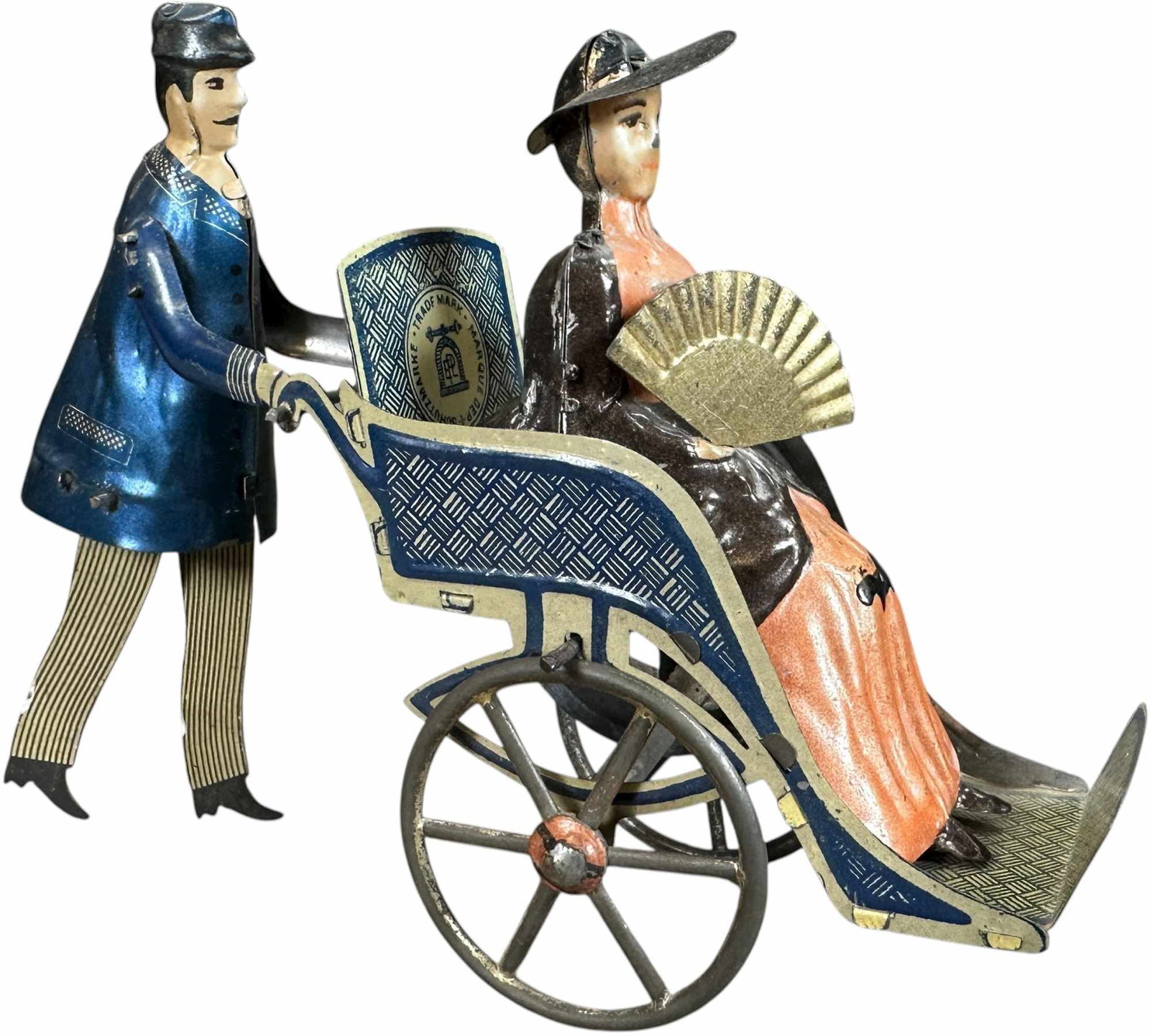 LEHMANN GOING TO THE FAIR: 299. LEHMANN GOING TO THE FAIR | Germany, string pulled flywheel mechanism, cart rolls as lady fans herself. | 6.5" l. | Great original (Pristine Condition) | $700 - $1,000