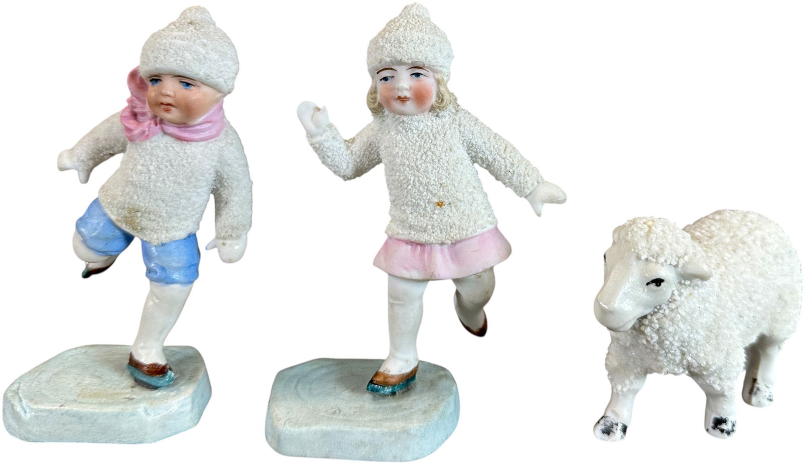 THREE PORCELAIN SNOW FIGURES: 1162. THREE PORCELAIN SNOW FIGURES | Two snow children with a standing sheep. | 4.5" h. | (Pristine Condition) | $300 - $600