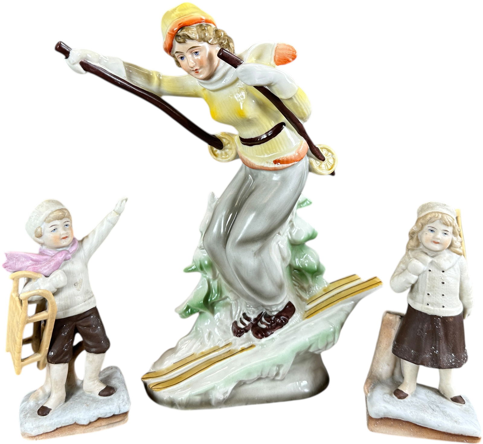 THREE CERAMIC SNOW FIGURES: 1300. THREE CERAMIC SNOW FIGURES | Two sledding, one skiing figure. | 9" h. | (Excellent Condition) | $300 - $600
