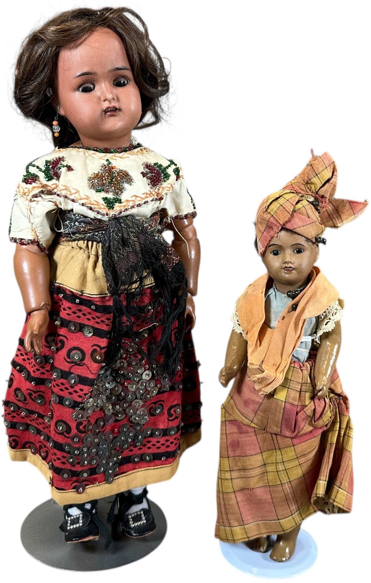 TWO EARLY 2OTH CENTURY BROWN BISQUE HEAD DOLLS: 1501. TWO EARLY 2OTH CENTURY BROWN BISQUE HEAD DOLLS | Larger doll is incised "K(star)R36", with sienna colored head and matching jointed body, colorful and creative costume, evoking a "gypsy" flavor,