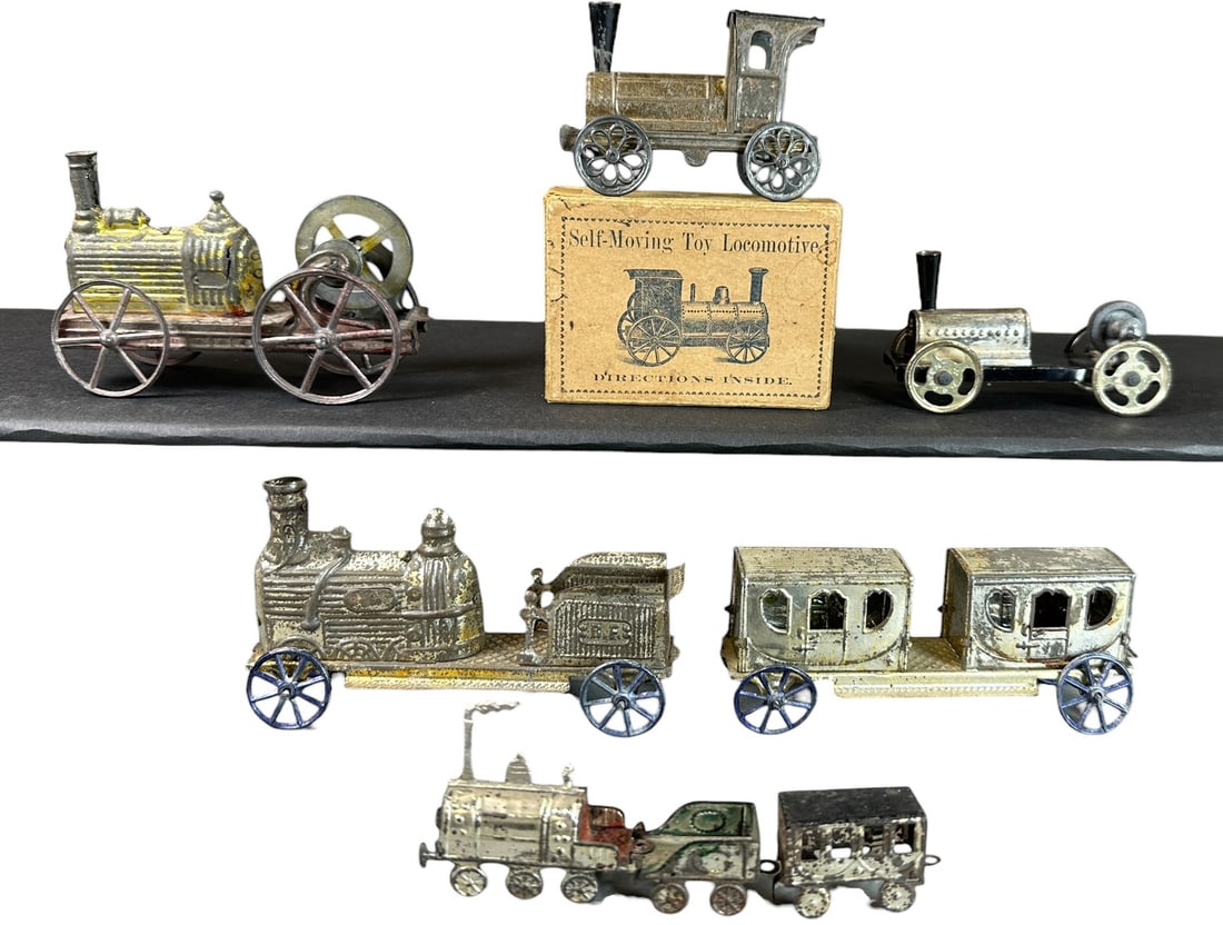 GROUP OF HESS & OTHER EARLY FLOOR TRAINS: 152. GROUP OF HESS & OTHER EARLY FLOOR TRAINS | Two Hess flywheel driven locomotives, rare original box and instructions for Hess flywheel loco, several other early penny toy trains. Provenance: The C