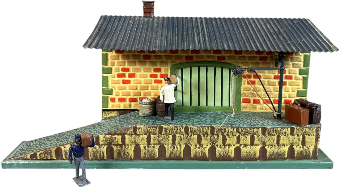 MARKLIN HAND PAINTED FREIGHT STATION: 316. MARKLIN HAND PAINTED FREIGHT STATION | Germany, Gauge 0, hand painted with colorful brickwork, includes several nice figures and luggage pieces. | 7" d. x 13.5" w. | Blue roof has some overpaint,