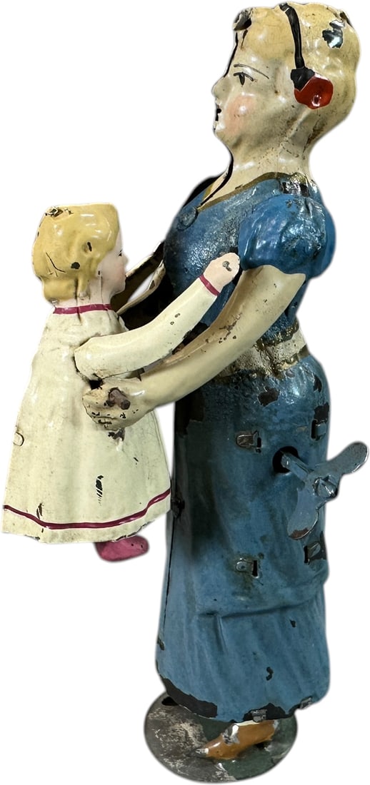 GUNTHERMANN MOTHER LIFTING CHILD: 1138. GUNTHERMANN MOTHER LIFTING CHILD | Germany, wind-up driven action, hand painted tin. Provenance: The Maloy Collection. | 7.5" h. | Woman is original while her arms and the child are professional