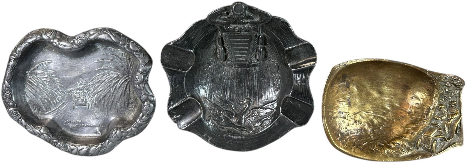 THREE EARLY AUTOMOBILE-THEMED ASHTRAYS: 130. THREE EARLY AUTOMOBILE-THEMED ASHTRAYS | circa 1905?1925. Three ashtrays, each featuring an early automobile in relief, including souvenir and scenic examples reflecting the public's fascination 