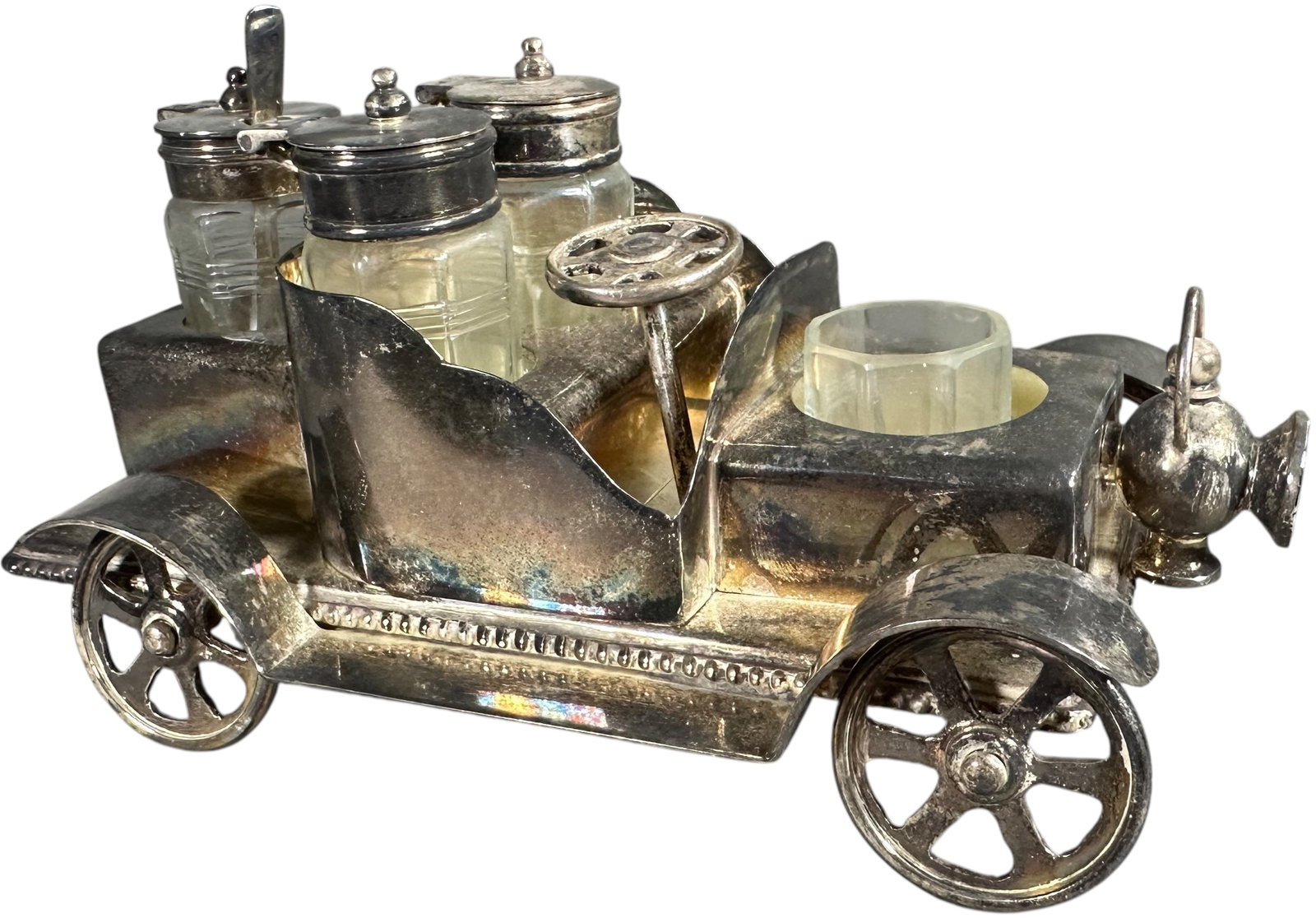SILVER PLATE AUTOMOBILE CRUET SET: 168. SILVER PLATE AUTOMOBILE CRUET SET | Silver-plated novelty cruet set in the form of an open touring automobile, complete with three lidded glass condiment jars, frosted glass tumbler, steering whe