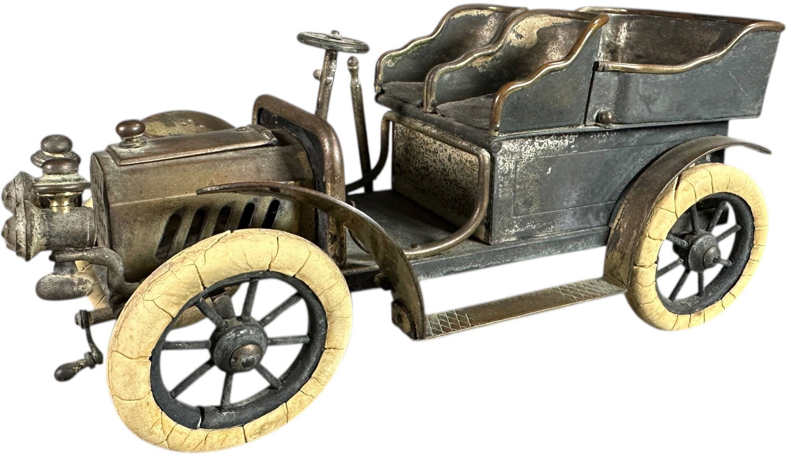 AUTOMOBILE CIGARETTE AND MATCH HOLDER: 170. AUTOMOBILE CIGARETTE AND MATCH HOLDER | circa 1905?1915. Cast metal automobile-form cigarette and match holder modeled as an open touring car with hinged rear compartment for cigarettes and a fli