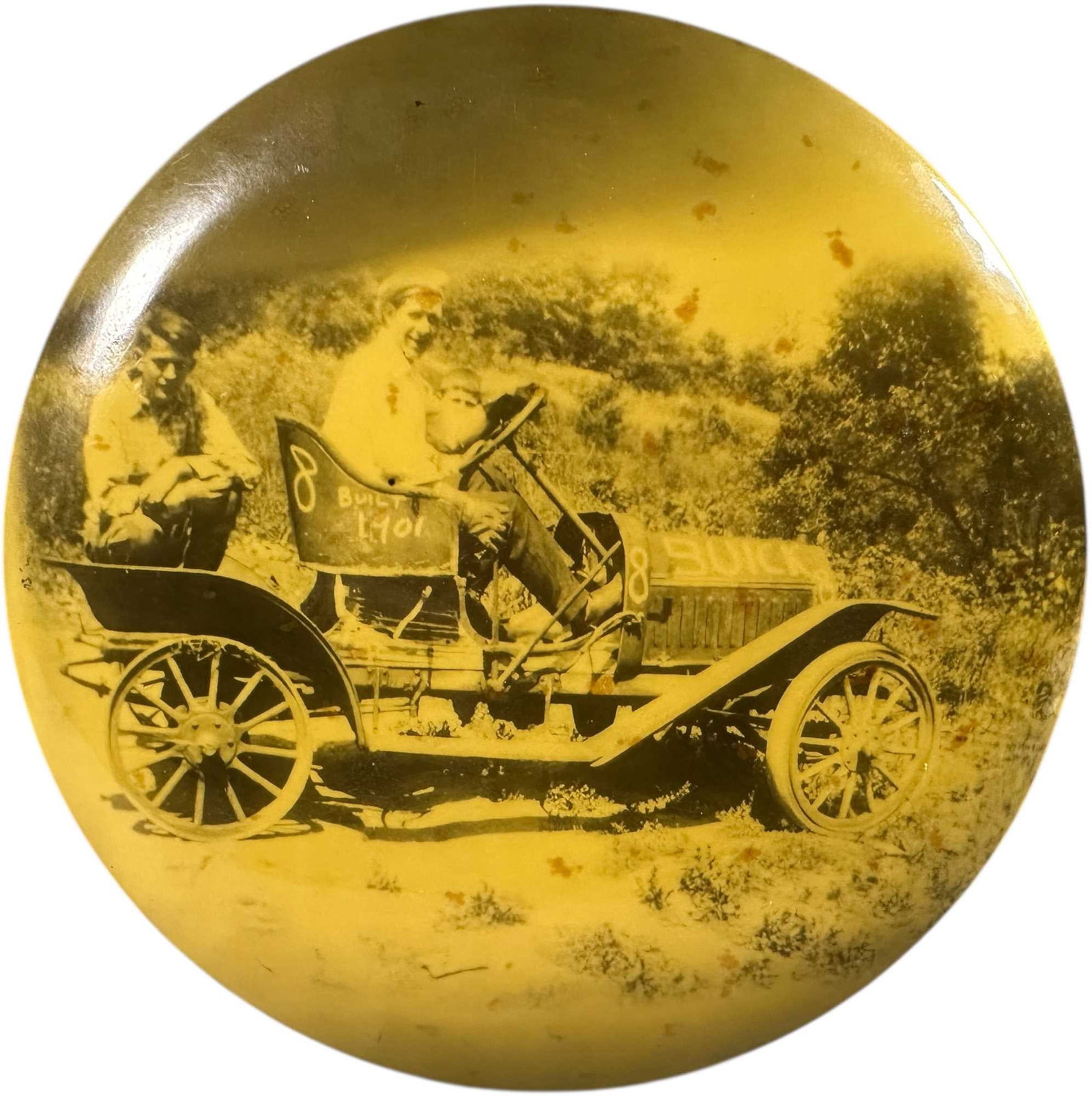 AUTOPOLO PHOTOGRAPHIC CELLULOID BUTTON: 261. AUTOPOLO PHOTOGRAPHIC CELLULOID BUTTON | Celluloid photographic button depicting two occupants aboard a stripped-down Buick automobile prepared for an auto polo match, with hand-painted race numb