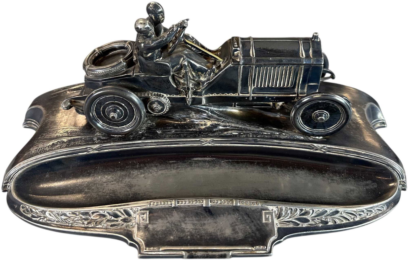 AUTOMOBILE FIGURAL INKWELL: 310. AUTOMOBILE FIGURAL INKWELL | circa 1910?1920. Silver-plated figural inkwell depicting a chauffeur-driven Brass Era touring automobile mounted on an integrated pen tray. The hinged hood conceals a