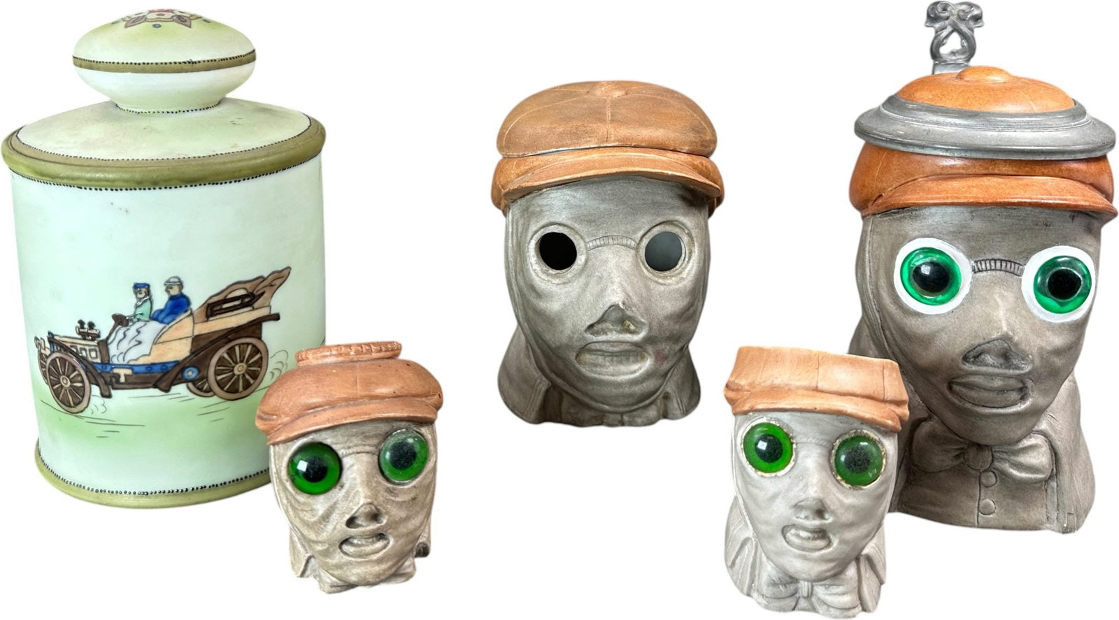 CHAUFFER TOBACCO JARS W/ TANKARD MUG: 350. CHAUFFER TOBACCO JARS W/ TANKARD MUG | From the David Bausch Automobilia Collection. | 7" h. | One jar missing eyes, otherwise (Excellent Condition) | $400 - $700