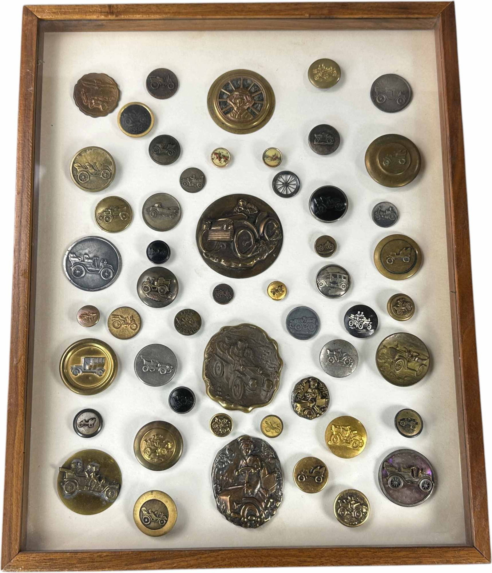 FRAMED COLLECTION OF AUTOMOBILE BUTTONS: 361. FRAMED COLLECTION OF AUTOMOBILE BUTTONS | Framed collection of approximately 50 automobile-themed buttons, featuring early touring cars, racers, chauffeurs, and motoring scenes in brass, celluloi