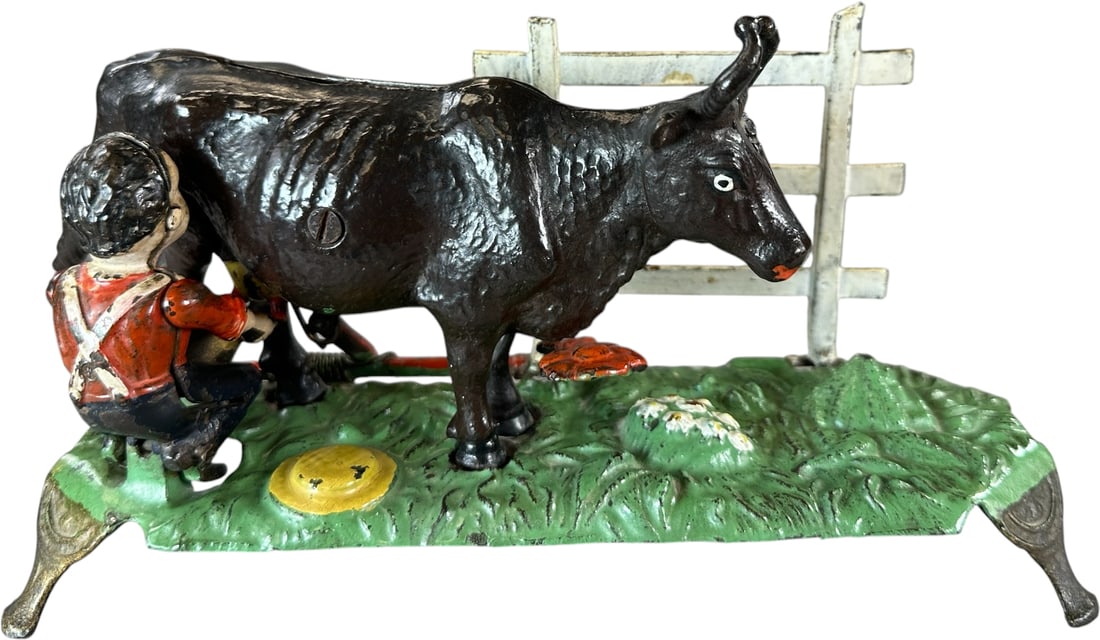 MILKING COW MECHANICAL BANK: 15. MILKING COW MECHANICAL BANK | J&E Stevens Co. Scarcer thin base version. One of the desirable pedestal series banks with a lot of moving parts, entertaining action depicts a man who is kicked back