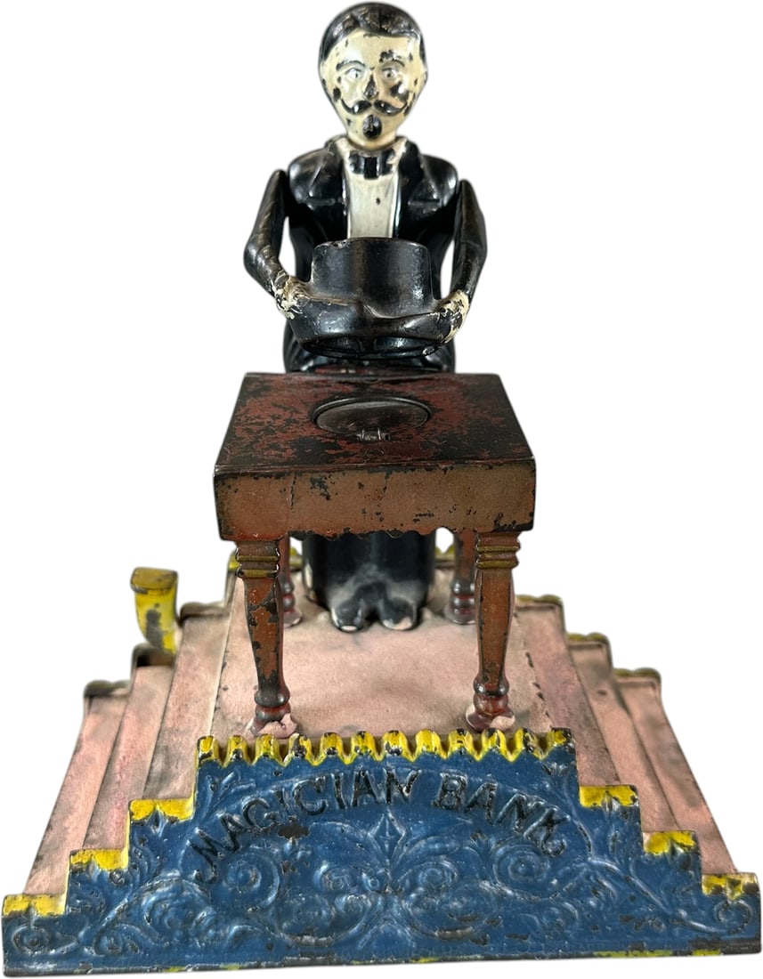 MAGICIAN MECHANICAL BANK: 32. MAGICIAN MECHANICAL BANK | J & E Stevens Co., the action of this bank demonstrates designer Charles Bailey's inventive mind, placing coin on table and pressing lever allows Magician to cover coin 