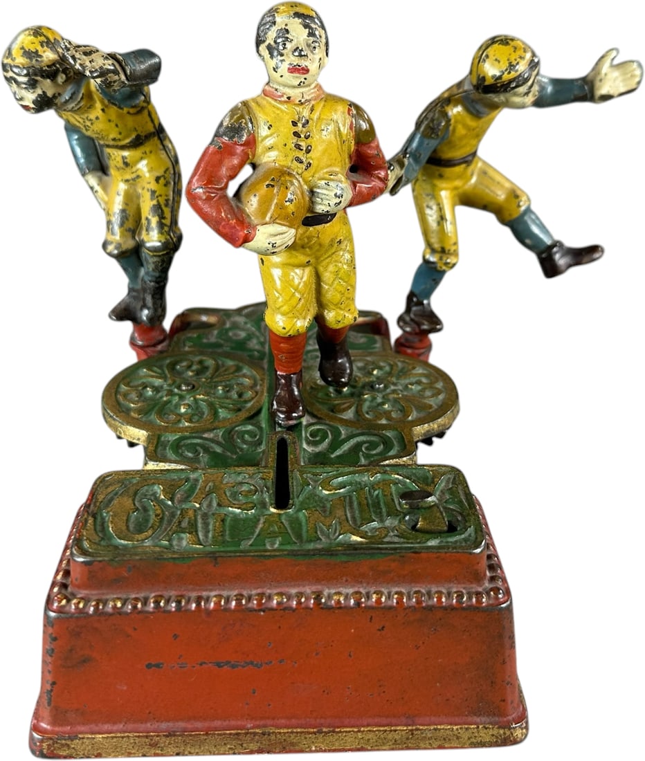CALAMITY MECHANICAL BANK: 55. CALAMITY MECHANICAL BANK | J&E Stevens Co., a casting marvel, depicts two football players awaiting to tackle the fullback with coin in slot, as they succeed, coin drops into slot for deposit - qu