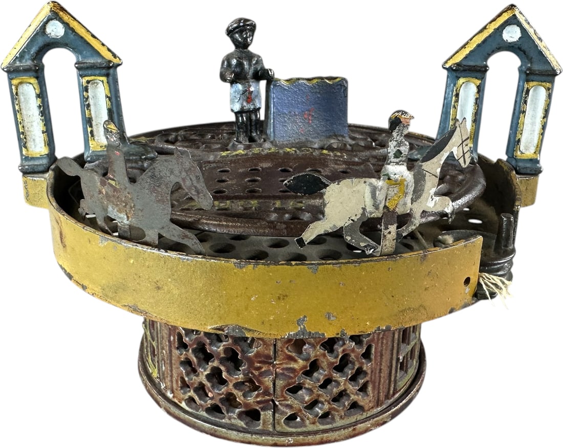 HORSE RACE MECHANICAL BANK: 59. HORSE RACE MECHANICAL BANK | J&E Stevens Co., pulling on string at front of bank sets the internal spring, dropping a coin into slot starts the horse race as tin sheet metal figures revolve around