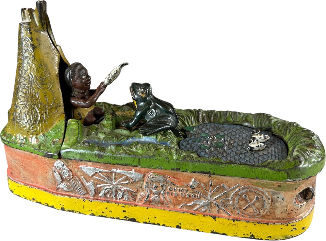 CHIEF BIG MOON MECHANICAL BANK: 64. CHIEF BIG MOON MECHANICAL BANK | J&E Stevens Co., a very popular bank with great casting and paint details to the grass and pond, action involves placing coin in slot and pressing lever which caus
