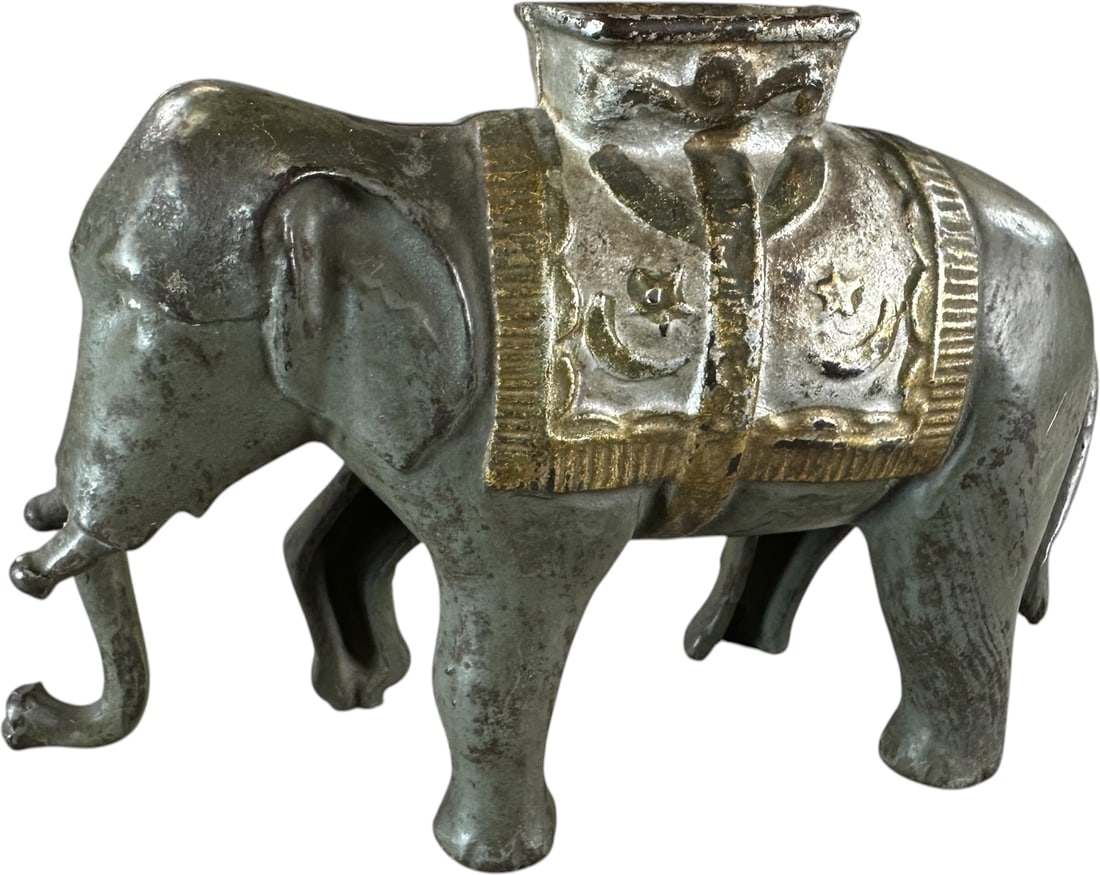 ELEPHANT SWINGS TRUNK MECHANICAL BANK: 99. ELEPHANT SWINGS TRUNK MECHANICAL BANK | AC Williams Co. circa 1905. Provenance: The Robert Booth Jr. Collection. | 5.5" h. | (Very Good Condition) | $75 - $150