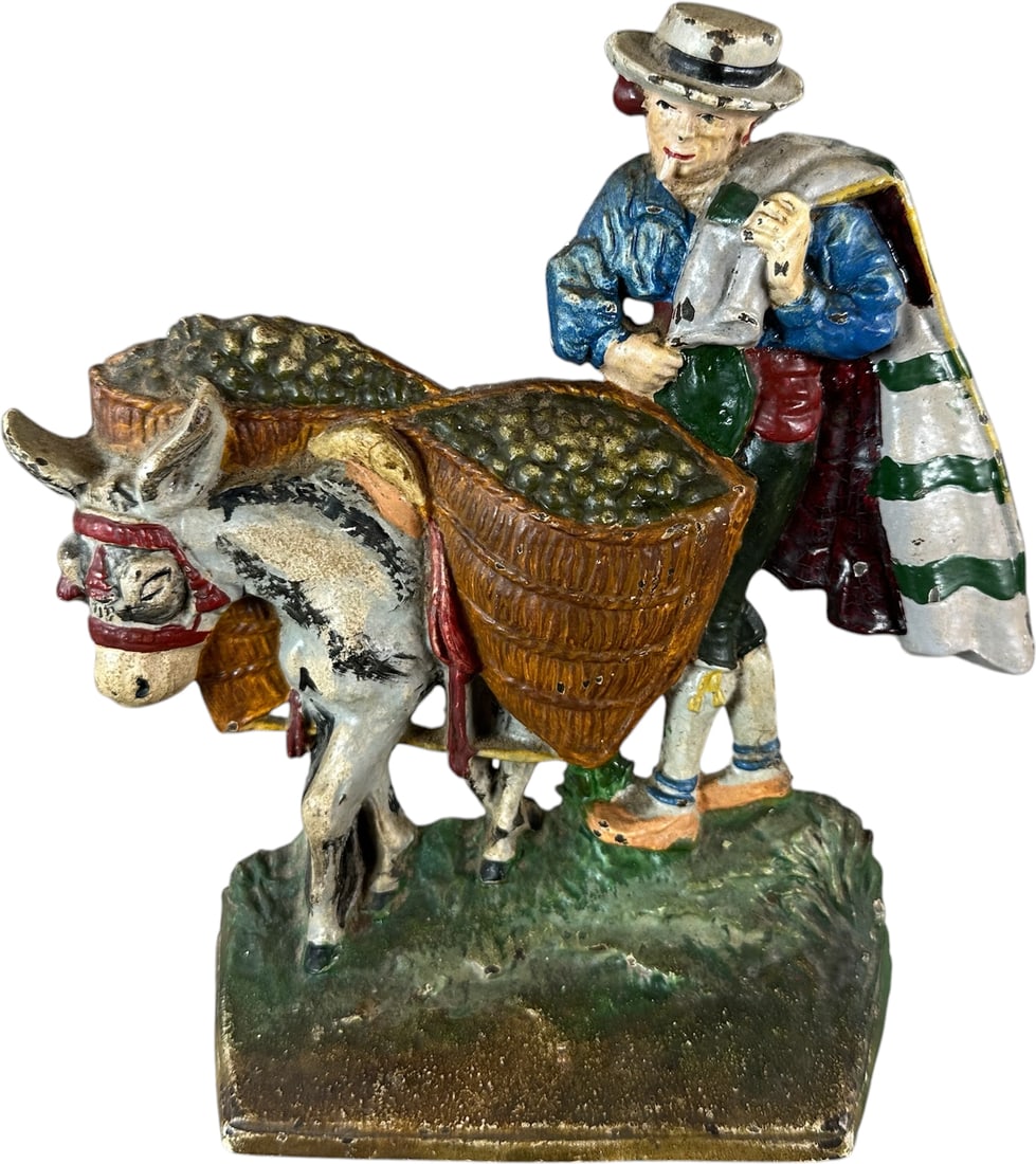 HUBLEY OLIVE PICKER DOORSTOP: 131. HUBLEY OLIVE PICKER DOORSTOP | Great casting design, well painted, depicts man in colorful clothing with donkey carrying baskets of olives. Ex: The Bob Brady Collection. | 8" h. | Great patina, (