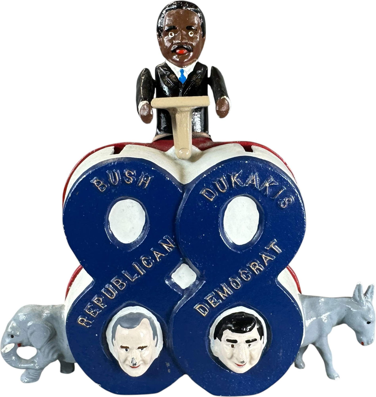 REYNOLDS BUSH DUKAKIS MECHANICAL BANK: 167. REYNOLDS BUSH DUKAKIS MECHANICAL BANK | "Campaign 88", Catalogue # 45-M, 1988, Edition 2 of 50. Ex: Max Berry Collection. | 9.5" h. | Still retains the cardboard tag from the Poughkeepsie NY 1988