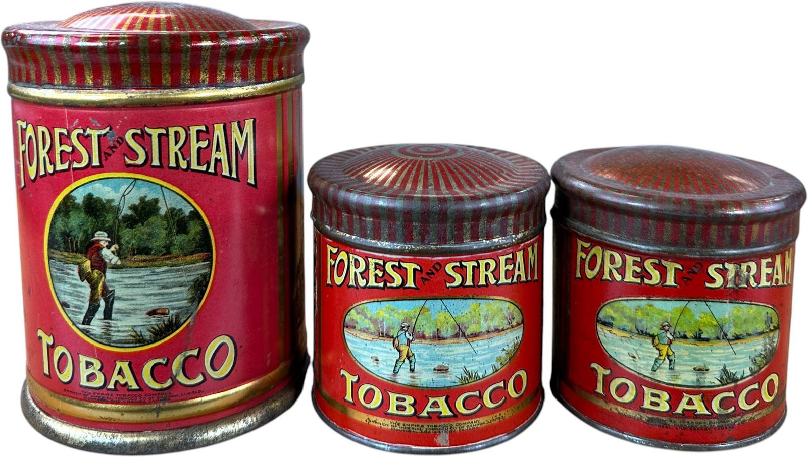 THREE FOREST & STREAM TOBACCO TINS: 139. THREE FOREST & STREAM TOBACCO TINS | Lithographed tins in graduated sizes, each featuring colorful sporting imagery of an angler fishing a wooded stream. | 5.5" h. | (Excellent Condition) | $200