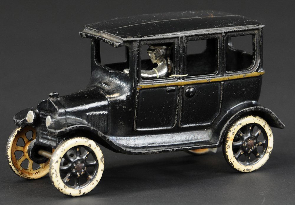 ARCADE FORDOR SEDAN: circa mid-1920's, cast iron, painted in black overall, gold trimmed stripe, seated nickel driver, black spokes, white painted wheels, silver headlights. 6 1/4" l.