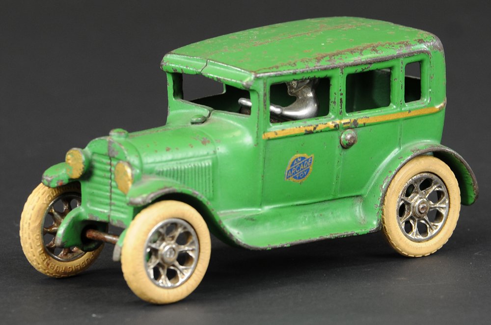 ARCADE FORD MODEL 'A' FORDOR SEDAN: Late 1920's, cast iron, painted in green, Arcade decal on door, gold striping, nickel spoke wheels with rubber tires, gold trimmed headlights. 6 1/2" l.