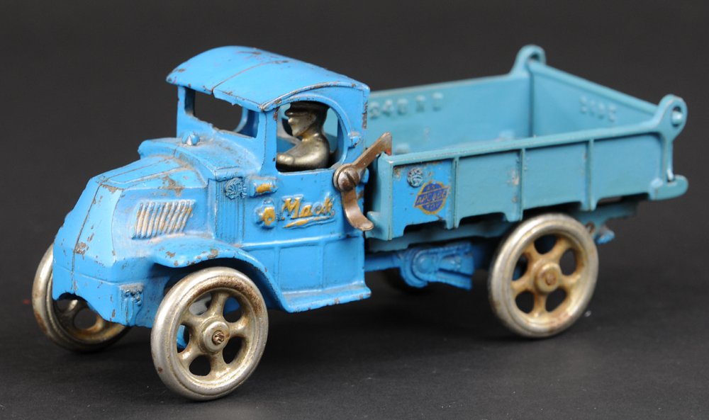 ARCADE MACK DUMP TRUCK: Cast iron, mid size, painted in blue overall, body tilts for unloading, nickel spoke wheels, seated driver, lever on side, Arcade decal on bed. 8 1/2" l.
