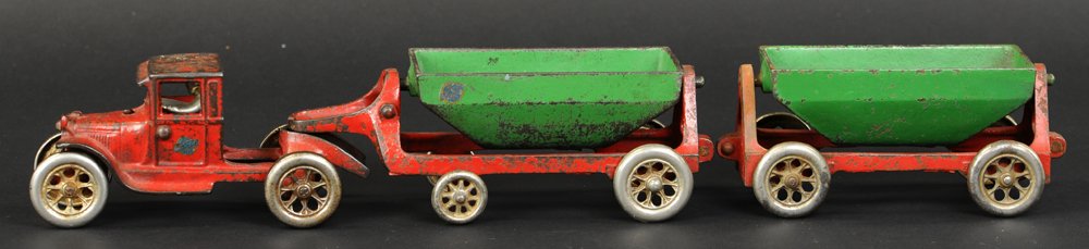 ARCADE TRUCK WITH SIDE DUMP TRAILER: Scarce toy, cast iron, enclosed Model 'A' Ford tractor with side dumping open cars in green on red frames, nickel spoke wheels. 20" l.