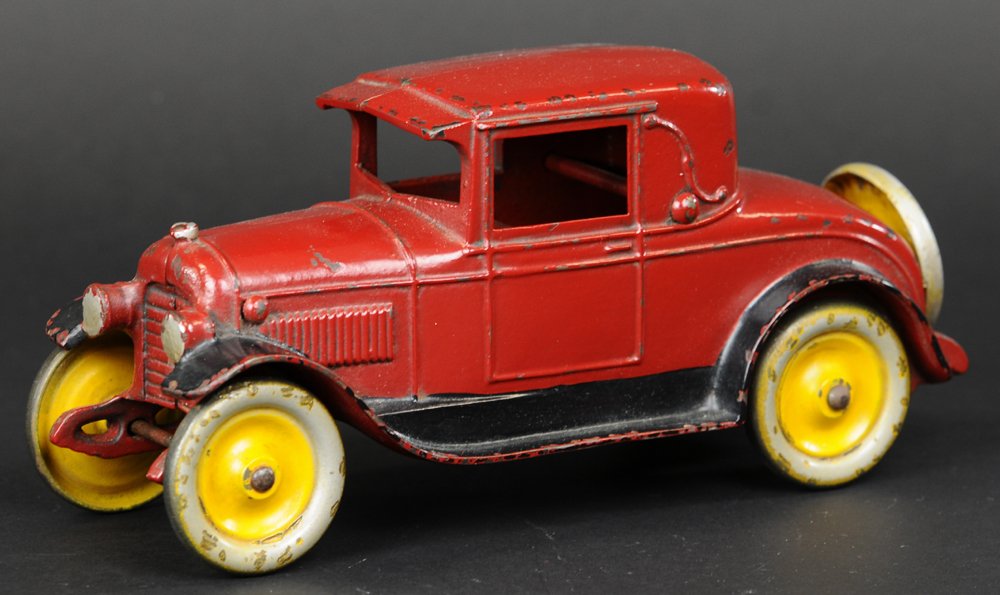 KENTON 1926 COUPE: Cast iron, done in red overall with black running boards, silver painted cast headlights, yellow and silver disc wheels, rear mounted spare. 10" l.