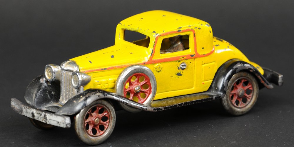 REO COUPE: Arcade, cast iron, done in bright yellow, red striping, nickel grille and driver, nickel plated wheels with red spokes, spare wheels side mounted, opening rumble seat. 9" l.