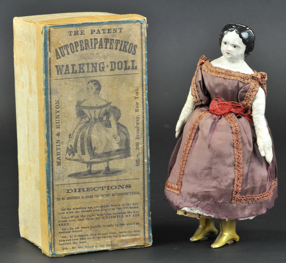 BOXED AUTOPERIPATETIKOS WALKING DOLL: Pat. 1862, Martin & Runyon, bisque head, full dress, brass boots, clockwork mechanism controls walking motions, very interesting toy. 10" h.