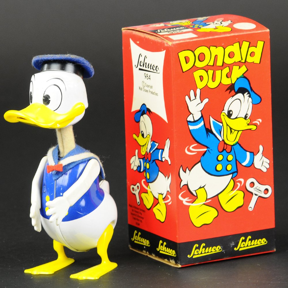 SCHUCO DONALD DUCK: Western Germany, boxed example, © Walt Disney Productions, brightly painted tin body with plastic feet, arms & beak, waddles while opening & closing mouth when wound. 6" h.