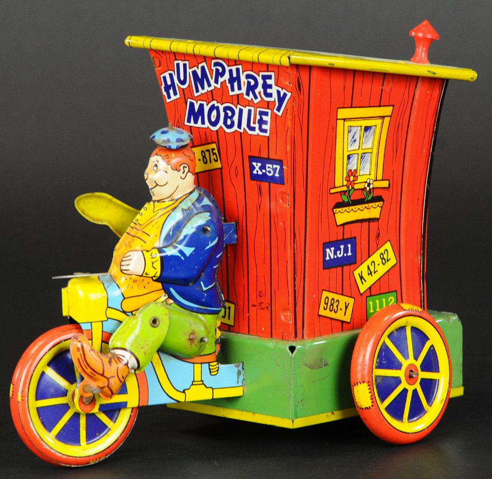 HUMPHREY MOBILE: Wyandotte, colorful lithographed tin comic toy, depicts outhouse on wheels with Humphrey at wheel of tricycle, clockwork driven. 8 1/2" l.