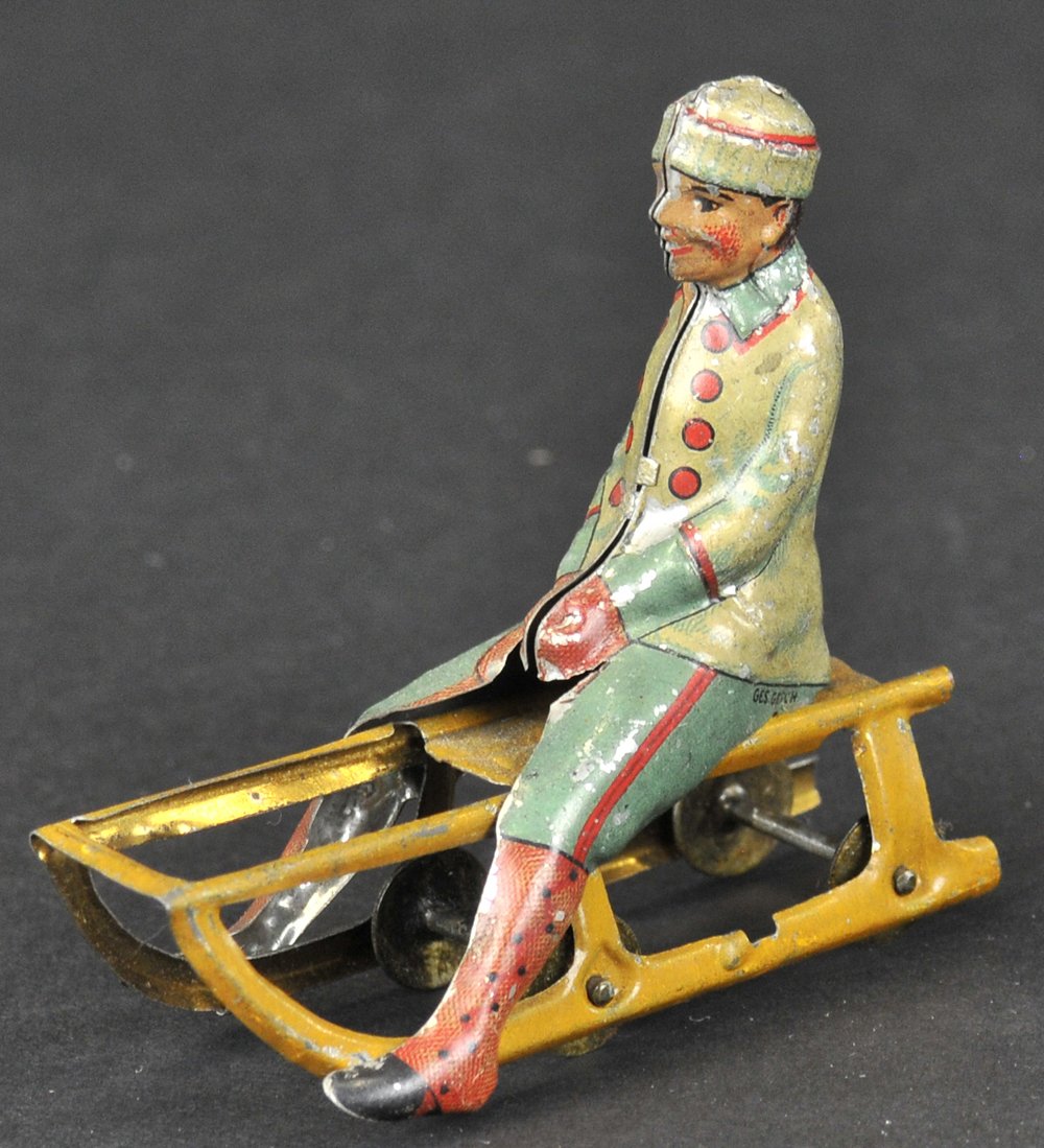BOY ON SLED PENNY TOY: Meier, Germany, embossed lithographed tin, nicely scaled example, depicts boy riding sled with wheels under runners, very colorful. 3" l.