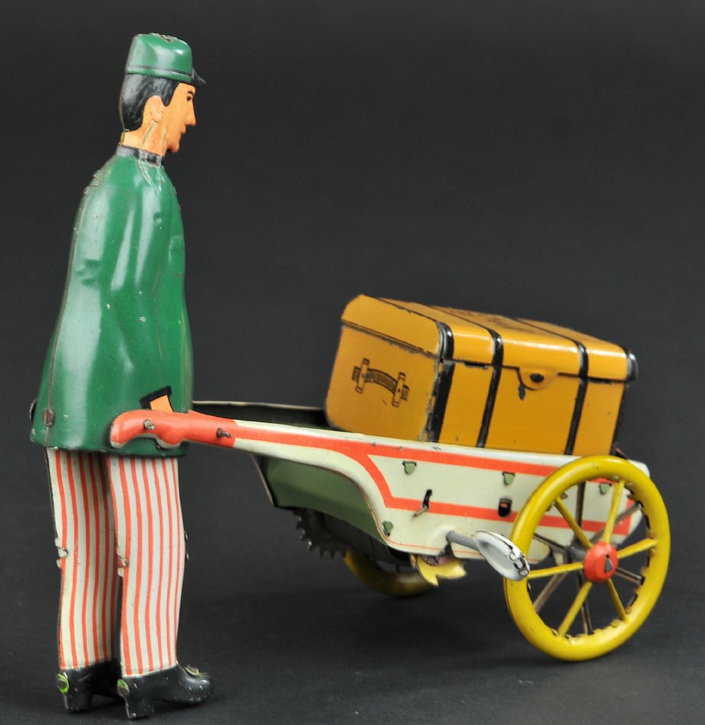 STOCK PORTER WITH LUGGAGE: Germany, lithographed tin and hand painted, full figure of porter pushing an open cart containing suitcase, clockwork driven. 6 1/2" l.