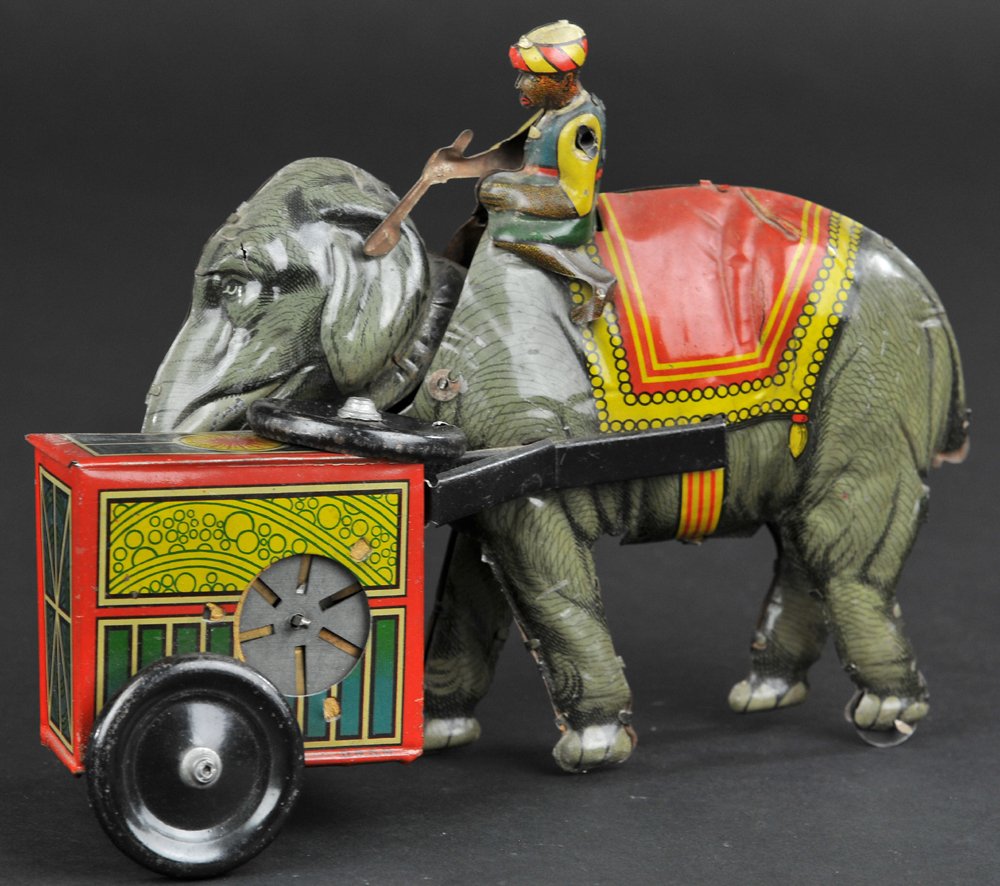 NATIVE ON ELEPHANT WITH MUISIC BOX: Hans Eberl, Germany, rare toy, lithographed tin, extensive detail to large music box on front wheels, clockwork driven, articulated head, seated figure on top with stick in hand. 8" l.