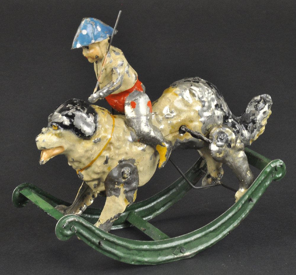BOY RIDING DOG ON ROCKER BASE: Germany, hand painted tin, amusing clockwork driven toy, depicts dog with curved runners able to rock when activated as boy sits holding stick in hand. 7" l.
