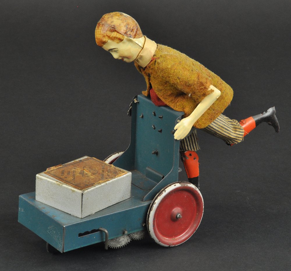 LE PETIT LIVREUR: Victor Bonnet, France, hand painted and cloth dressed figure, depicted with loaded cart, disc wheels, clockwork driven, wild action. 7" h.