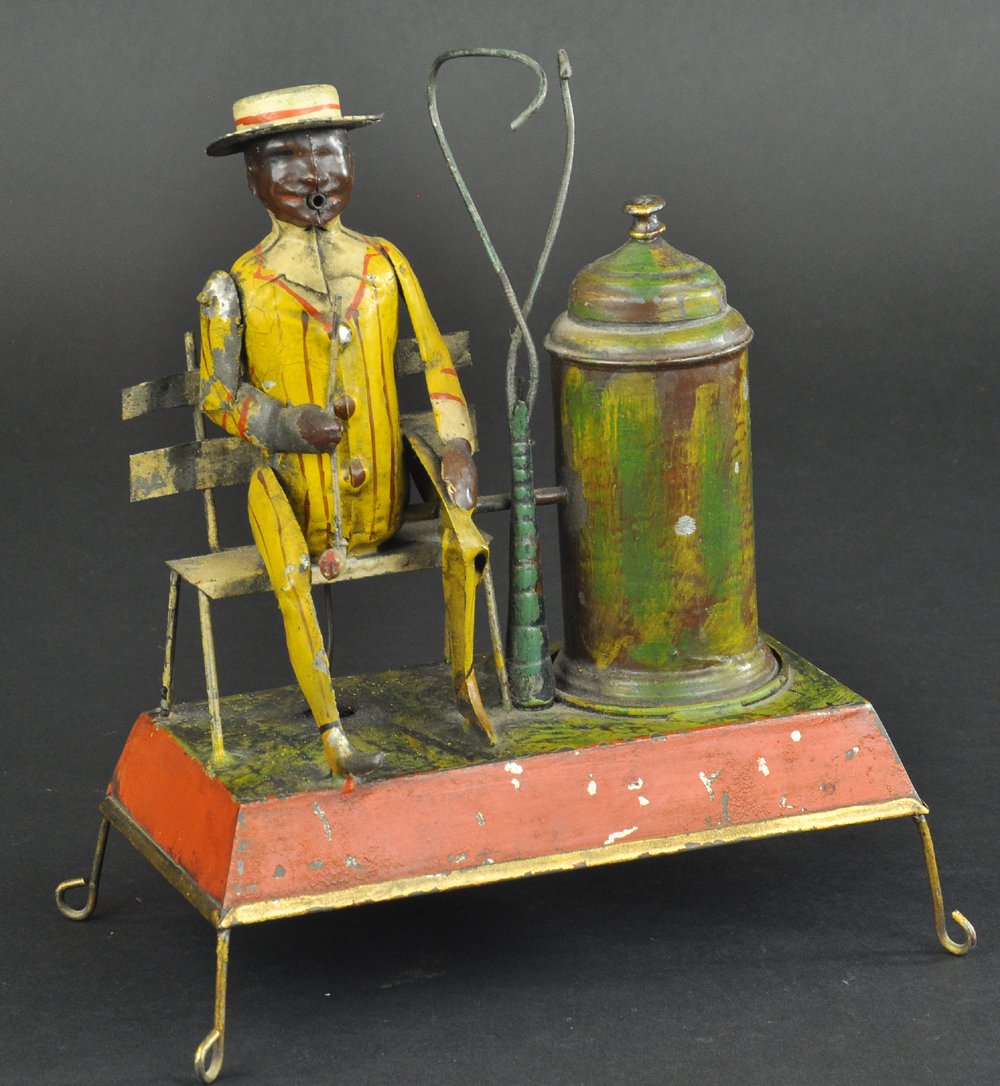GUNTHERMANN MAN SMOKING & SEATED ON BENCH: Germany, a very curious painted tin example, clockwork activated, intense action involves smoke pushed through tube in shared smoke chamber which appears to come from gentleman's mouth as he lowers an