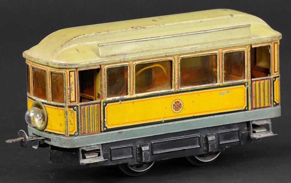 CARETTE TROLLEY: Germany, electric tram done in lithographed body, yellow body, green painted opening roof, clerestory on top and side designation holders, celluloid windows. 8" l.