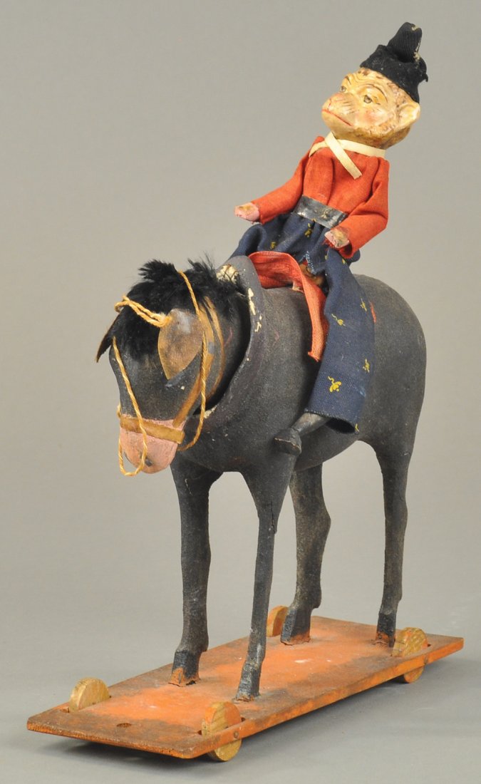 MONKEY ON DONKEY PULL TOY: German platform toy, nodding donkey with stick legs, with well dressed composition monkey riding on top. 10" l.